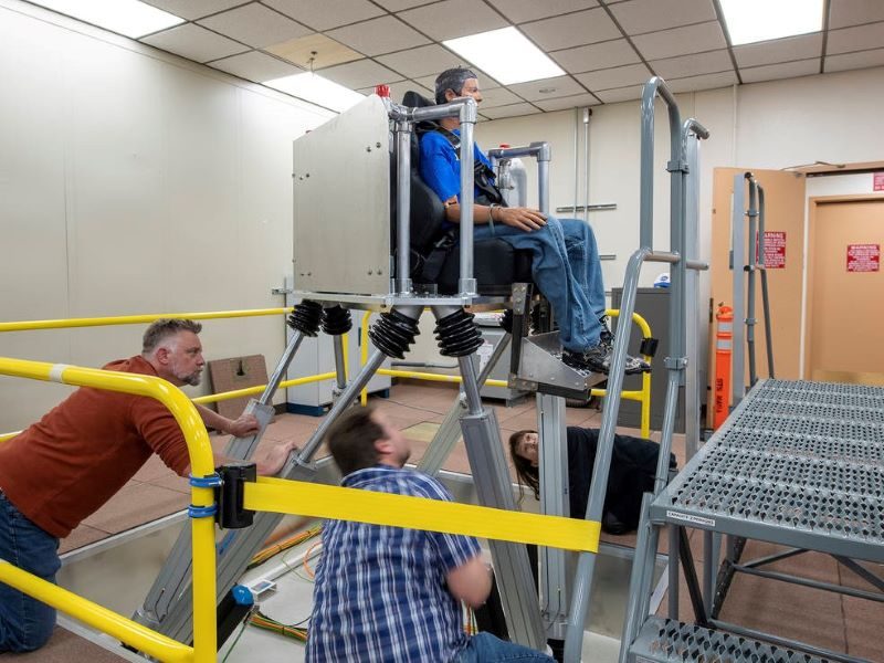 NASA researchers Jeanette Le, Curt Hanson, and Erik Waite, look on as pieces of a newly installed motion simulator are tested at NASA Armstrong Flight Research Center
